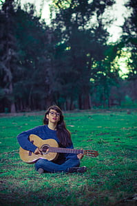 woman sitting on grass while playing guitar thumbnail