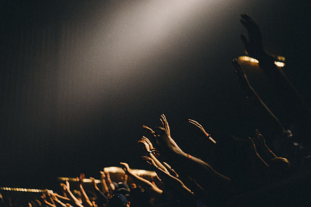 photography of people raising hands in dim concrete building thumbnail