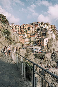 people walking beside guard rail near white and brown concrete buildings during daytime thumbnail