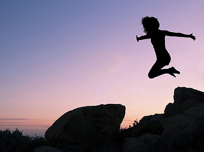 silhouette of girl jumping in front of rock thumbnail