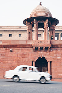 white sedan passing brown architectural structure at daytime thumbnail
