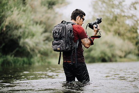 man standing in body of water holding DSLR camera thumbnail