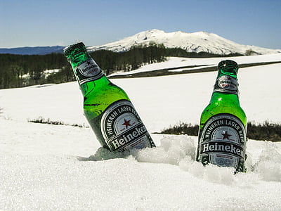 two Heineken beer bottles in snow field far away snow mountain thumbnail