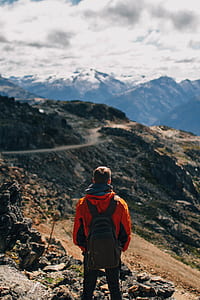 man standing on cliff facing mountain thumbnail