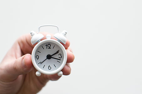 person holding white analog desk clock thumbnail