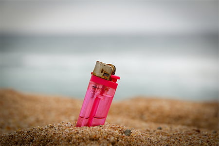 pink disposable lighter buried in sand thumbnail