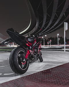 red and black sports bike parked under bridge during night thumbnail