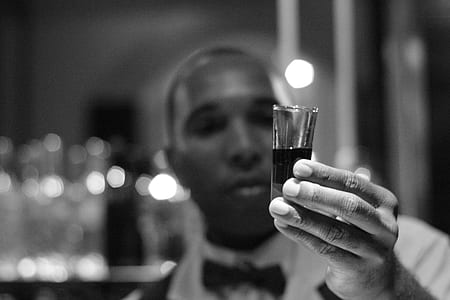shallow focus photography of man holding clear shot glass thumbnail