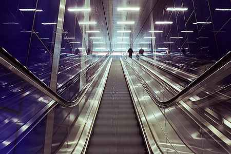 silhouette of man on grey escalator inside building thumbnail