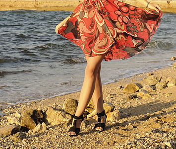 woman holding her dress while walking on beach thumbnail