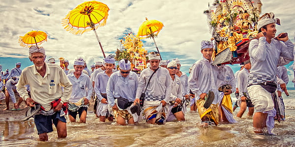 group of people crossing river while lifting figurine during daytime thumbnail