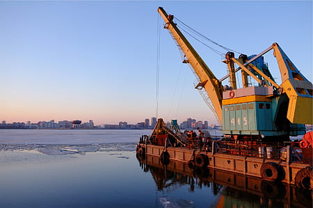 yellow and teal heavy equipment on body of water thumbnail