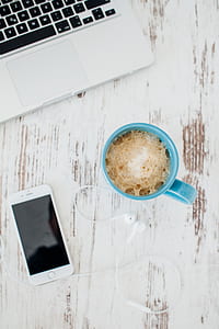 flat-lay photography of blue mug with coffee beside iPhone and EarPods on table thumbnail