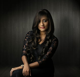 woman sitting near black wall thumbnail