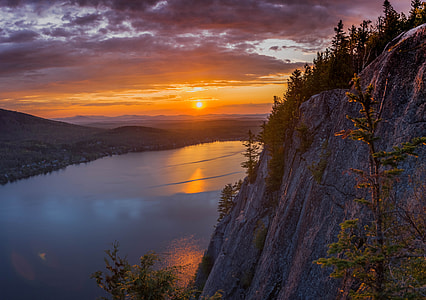 gray mountain cliff near lake during cloudy sky thumbnail