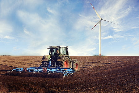 tractor with cultivator on field with turbine vent in distant thumbnail