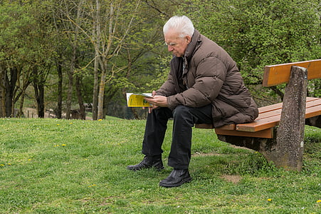 man sitting on the bench reading book thumbnail