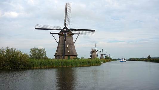 wind mills near lake with sailing motorized boat at daytime thumbnail
