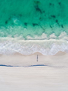 aerial photo of person walking on beach during daytime thumbnail