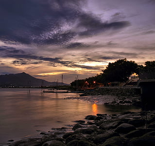 houses beside sea and bridge during golden hour thumbnail