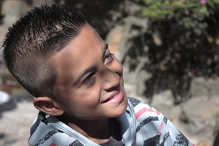 smiling boy sitting near wall thumbnail