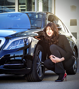 woman crouching beside black car during daytime thumbnail