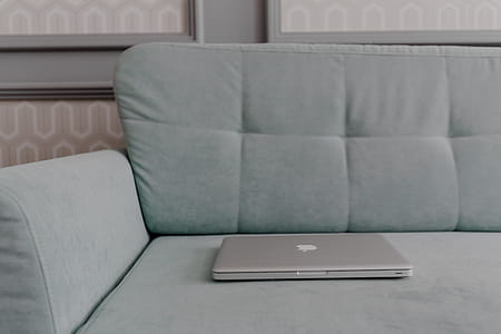 MacBook laptop lying on mint couch thumbnail