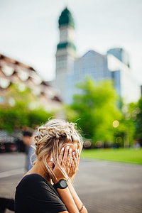 woman wearing black shirt and watch covering her face while sitting during day time thumbnail