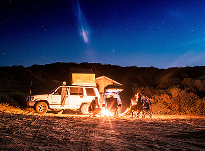 people camping beside white car during night time thumbnail