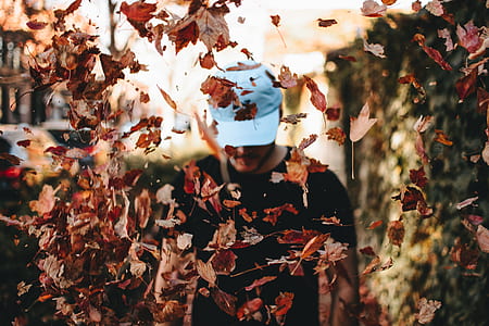 man wearing white hat standing in front of brown leafs thumbnail