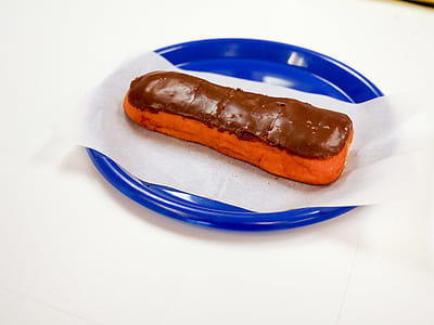 Eclair sitting on a blue plate with a white background thumbnail