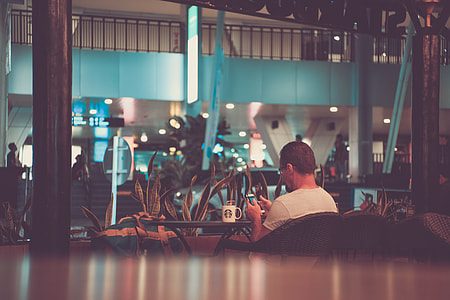 man wearing white shirt holding smartphone near brown wooden table thumbnail
