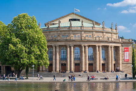 people outside brown building near body of water thumbnail