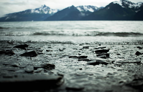 selective focus photography of rocky beach across mountains during daytime thumbnail