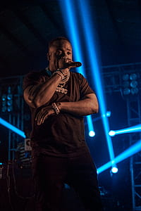 man standing on stage while holding microphone thumbnail
