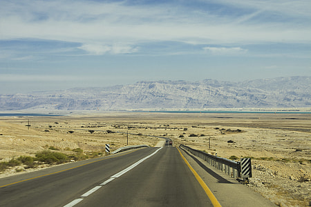 road near mountain under gray sky thumbnail