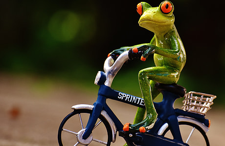 green ceramic frog playing bike figurine in closeup photography thumbnail