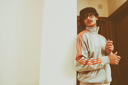 man standing leaning on white wall thumbnail