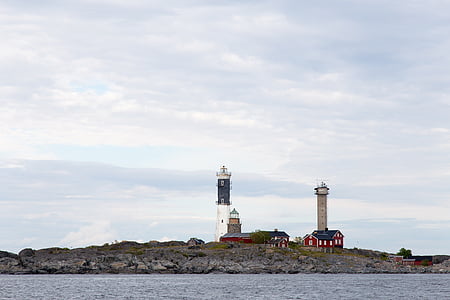 two white and brown lighthouse under white and blue cloudy skies at daytime thumbnail