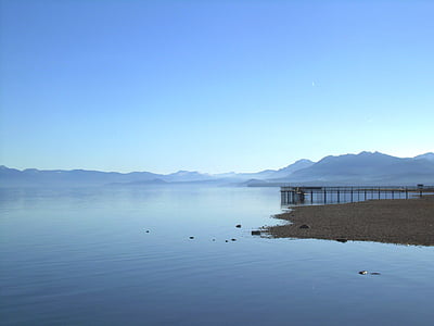 dock on calm body of water under blue sky thumbnail