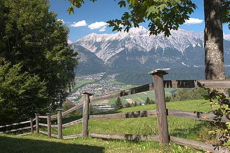 brown wooden fence near trees and mountain near town thumbnail