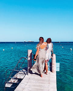 Two Women Standing On Wooden Dock thumbnail