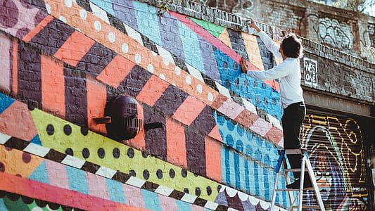 man in white shirt on ladder about to climb in graffiti wall thumbnail