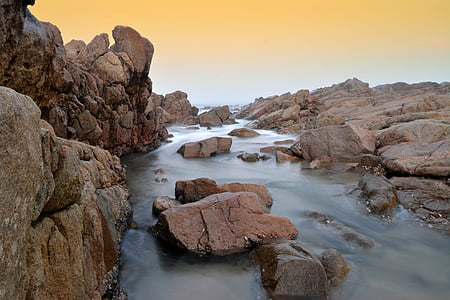 brown rock formation near body of water landscape photography thumbnail