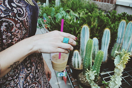 person holding glassware with liquid and straw thumbnail