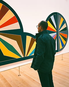 man in black shirt standing in front of wall art thumbnail