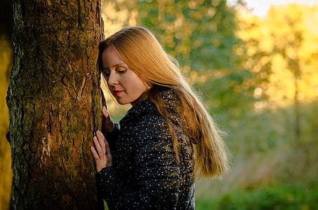 selective focus photography of woman in black top leaning on tree trunk thumbnail