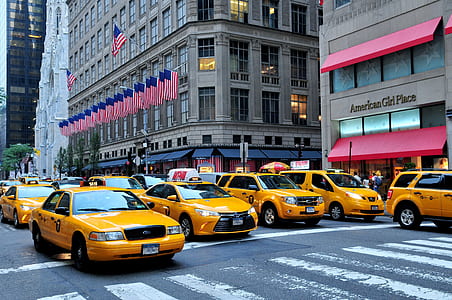 yellow cars on road near building with flag of America thumbnail