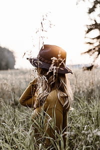 woman standing on field near tall grasses during daytime thumbnail