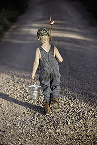 boy in blue denim overalls holding metal bucket and fishing rod thumbnail